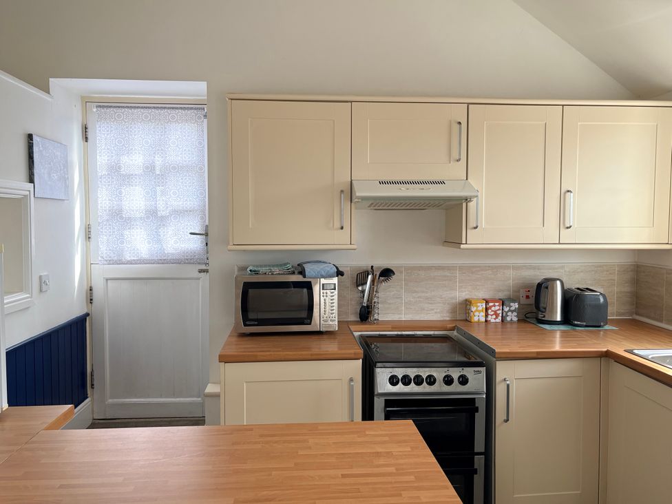 A kitchen with a microwave and a door at Lighthouse Cottage in St Erme near Truro