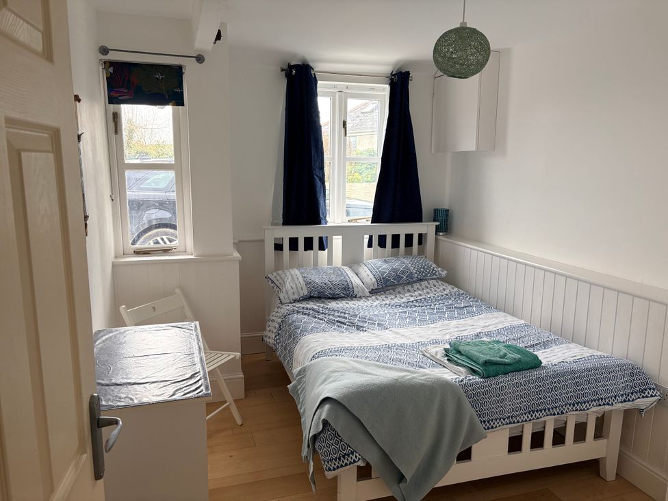 A bedroom with a bed and window at Lighthouse Cottage in St Erme near Truro
