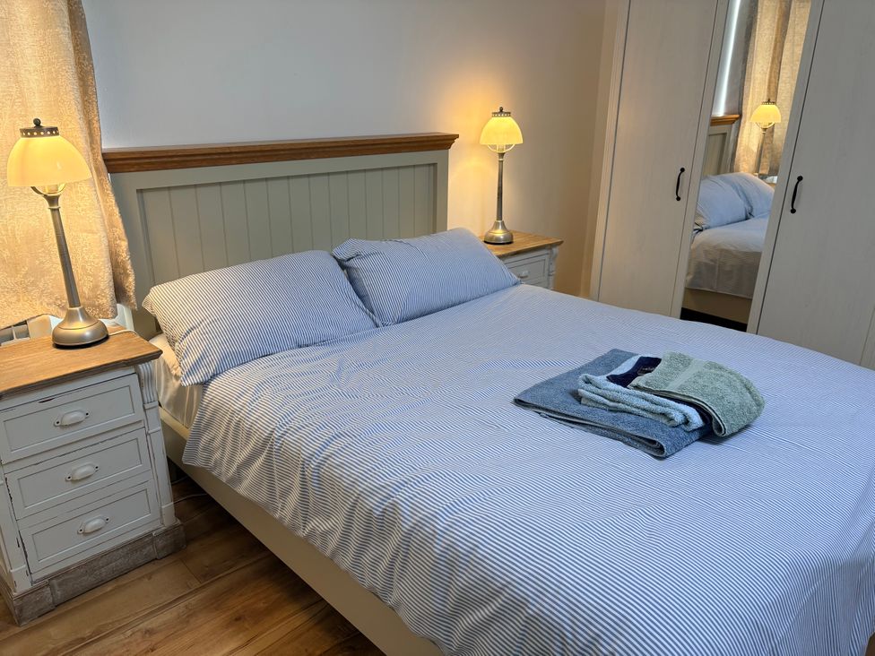 A bedroom with a bed and bedside tables at Lighthouse Cottage in St Erme near Truro