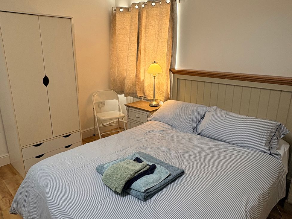 A bedroom with a bed and wardrobe at Lighthouse Cottage St Erme near Truro