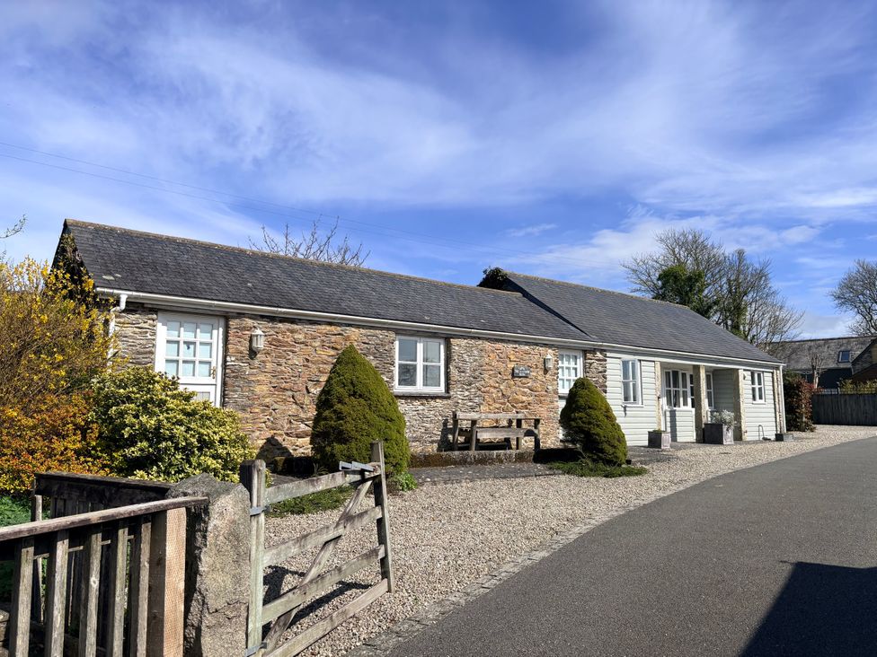 An outdoor view of a stone building with a bench and plants at Lighthouse Cottage in St Erme near Truro