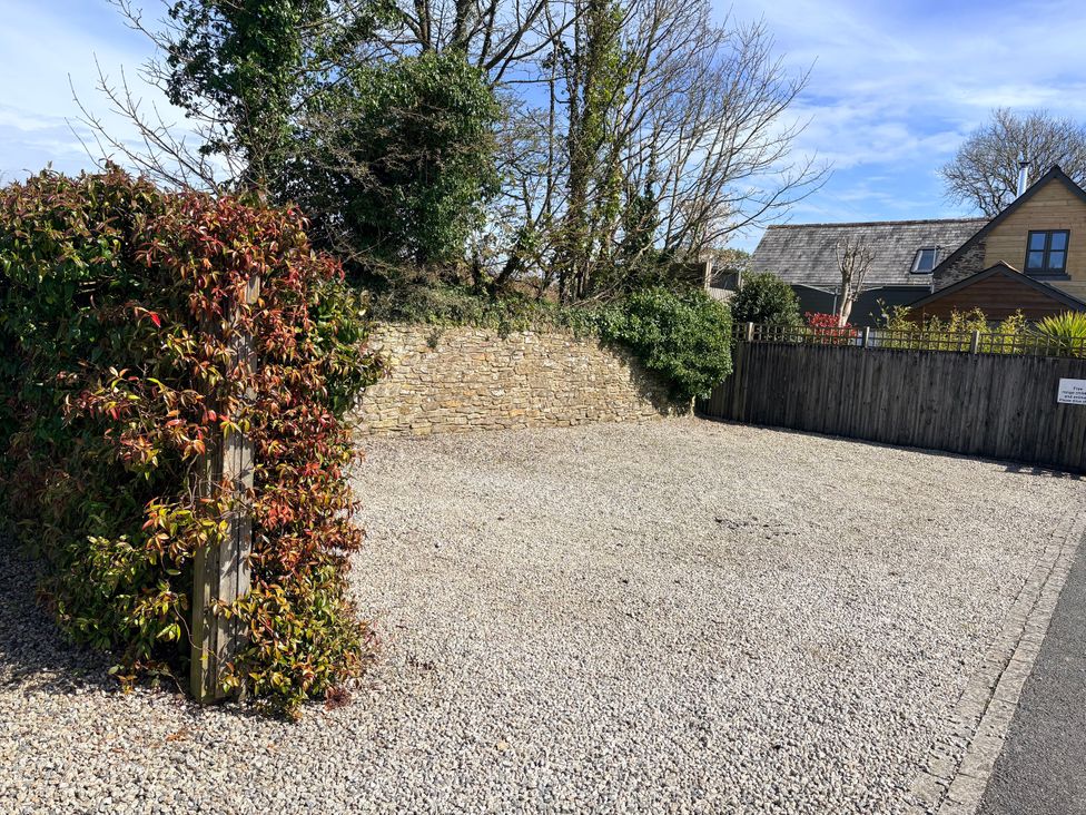 An outdoor space with gravel, a hedge, and a house at Lighthouse Cottage in St Erme near Truro