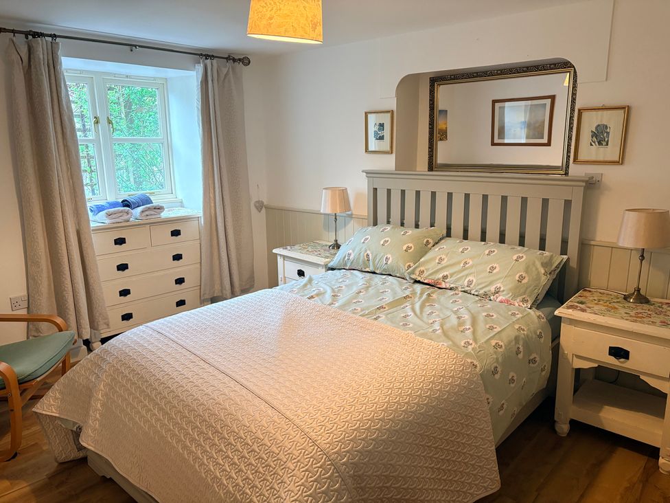 A bedroom with a bed and nightstand at Sunlight Cottage St Erme near Truro