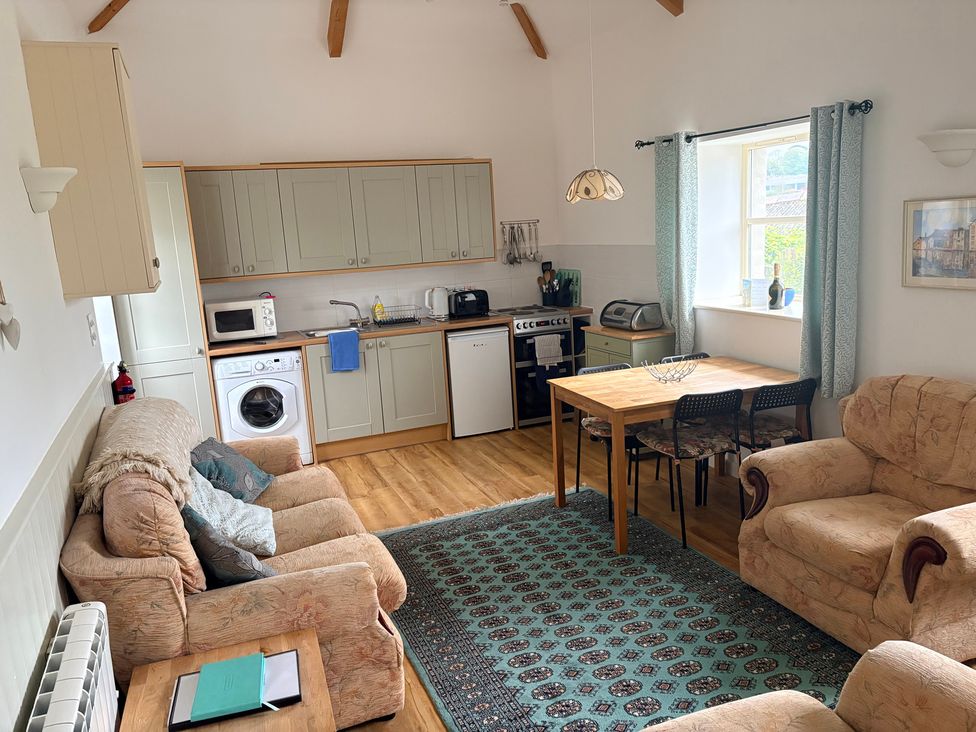 A kitchen and living area with seating and dining table at Sunlight Cottage in St Erme near Truro