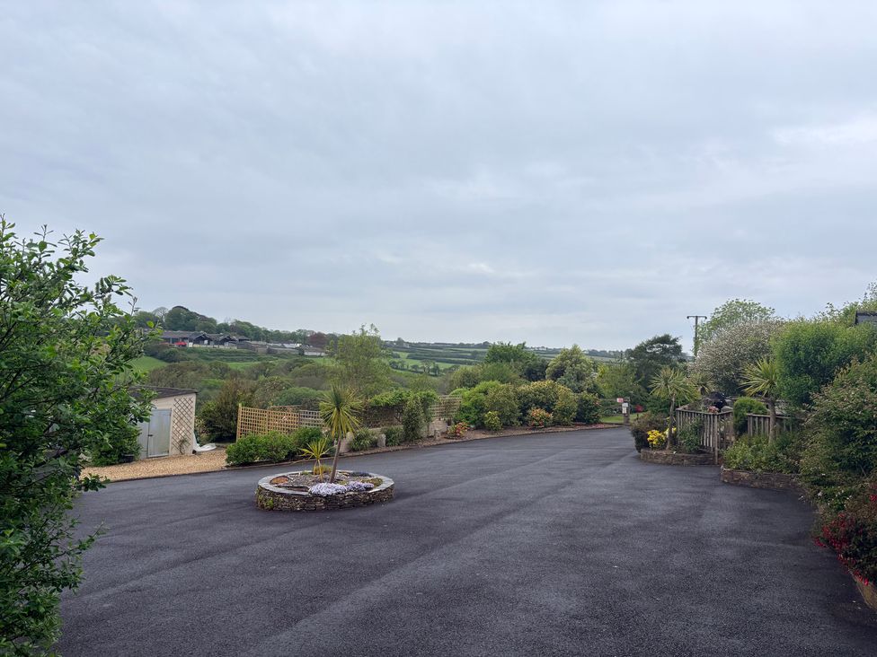 A garden with a driveway and flowering plants at Sunlight Cottage St Erme near Truro