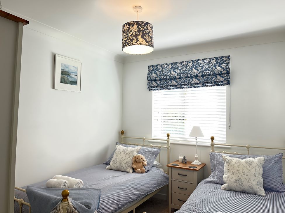 A bedroom with two beds and a nightstand at Breeze Cottage in Falmouth