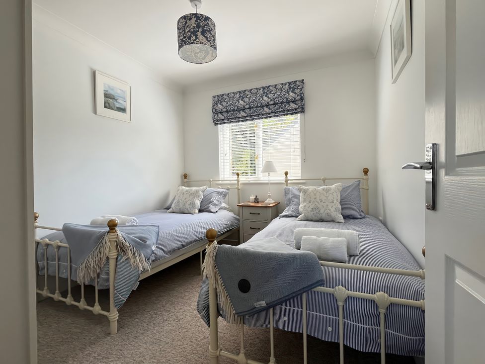 A bedroom with two beds and a window at Breeze Cottage in Falmouth