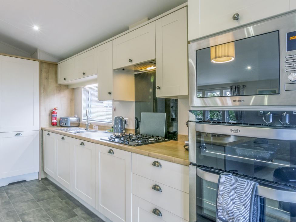 A kitchen with sink, gas stove, oven, and microwave at Lodge 58 at Riviera Bay Coastal Retreat Brixham