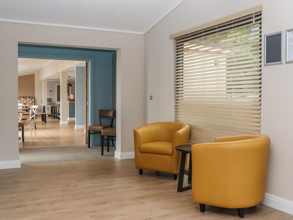 A lobby with yellow armchairs and a table at Lodge 69 at Riviera Bay Coastal Retreat Brixham