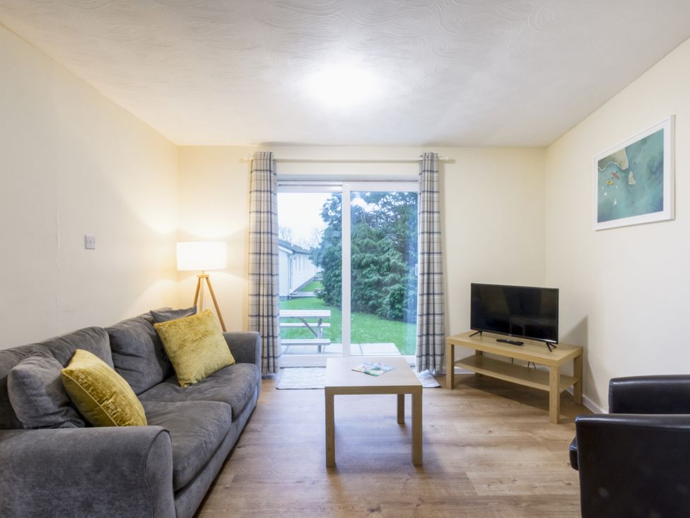 A living room with a sofa and television at Chalet 7 at Landscove Holiday Park, Brixham