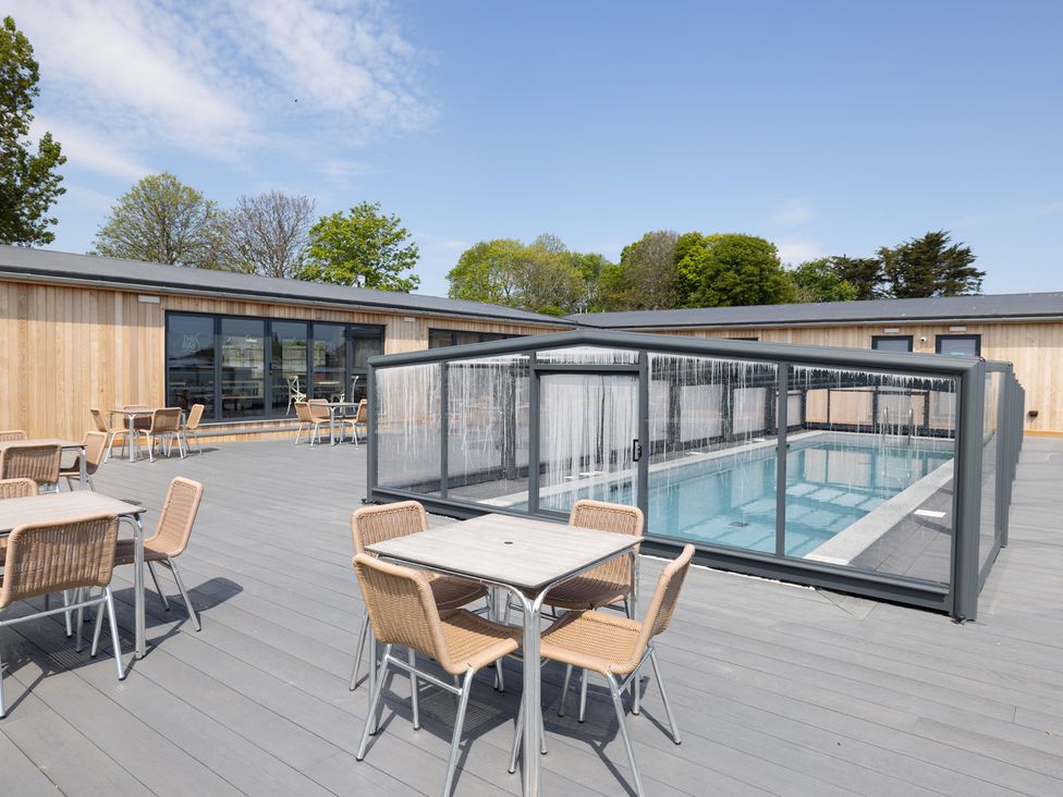 An outdoor area with a pool enclosure and seating at Chalet 7 at Landscove Holiday Park in Brixham