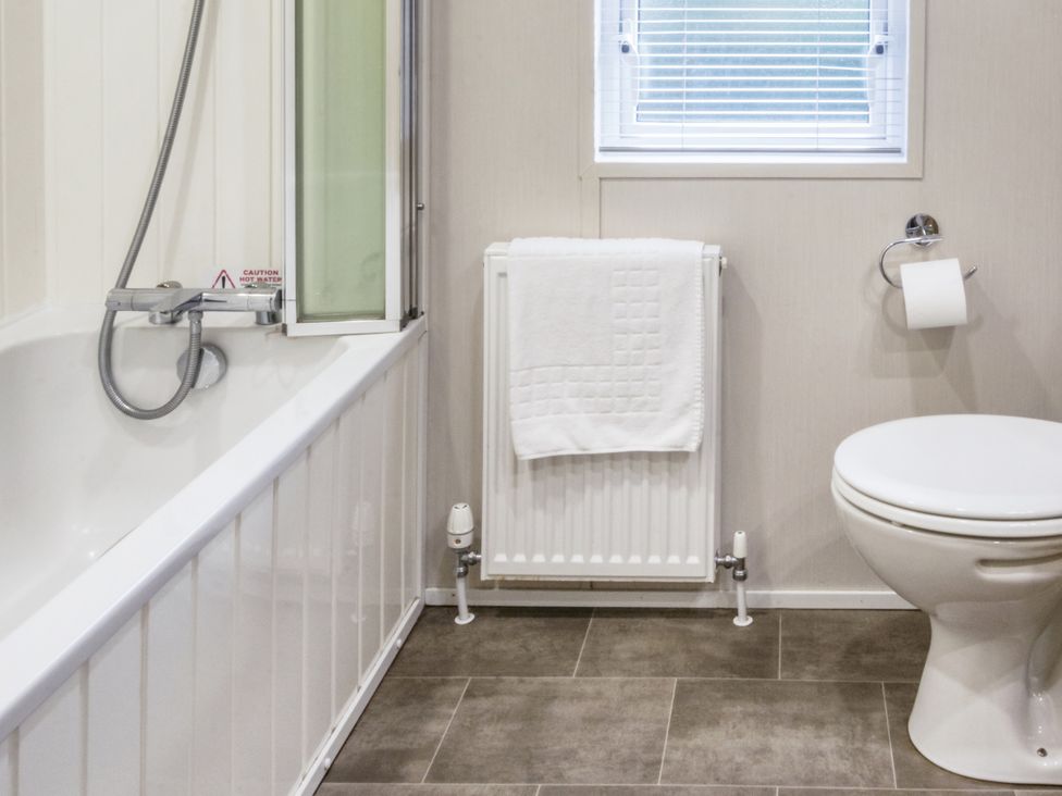 A bathroom with a bathtub and toilet at Lodge 72 at Riviera Bay Coastal Retreat Brixham