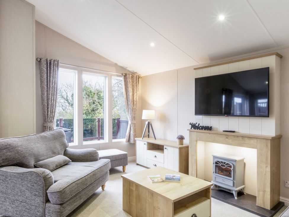 A living room with a sofa, television, and fireplace at Lodge 73 at Riviera Bay Coastal Retreat Brixham