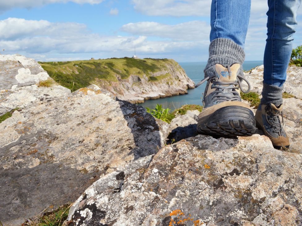 A person wearing hiking boots on rocks near water at Chalet 31 at Landscove Holiday Park Brixham