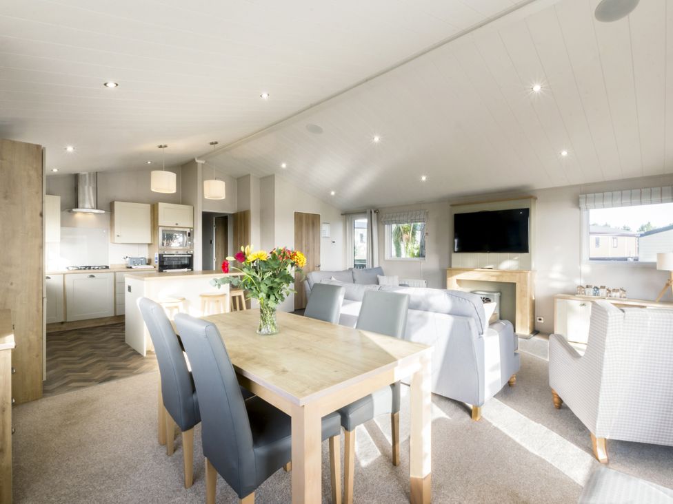 A living room with a dining table and kitchen area at Lodge 15 at Landscove Holiday Park Brixham
