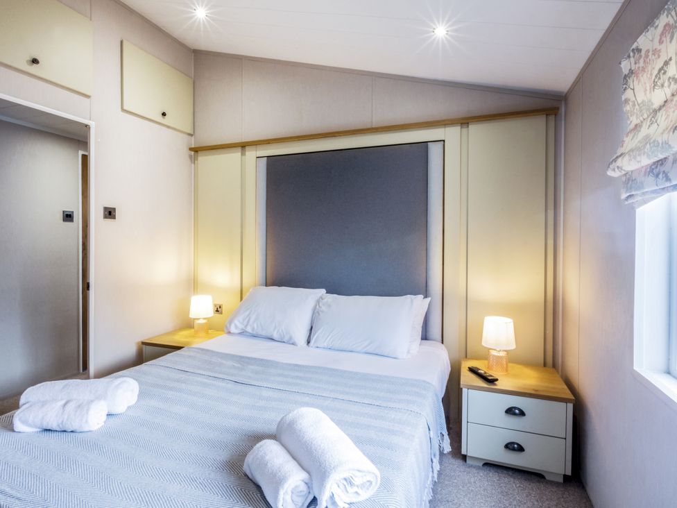 A bedroom with a bed and bedside table at Lodge 15 at Landscove Holiday Park Brixham