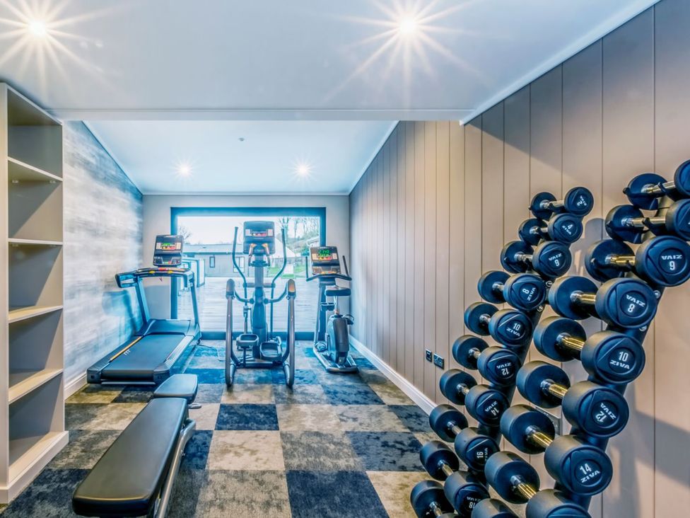 A gym with exercise equipment including a treadmill and dumbbells at Lodge 15 at Landscove Holiday Park Brixham