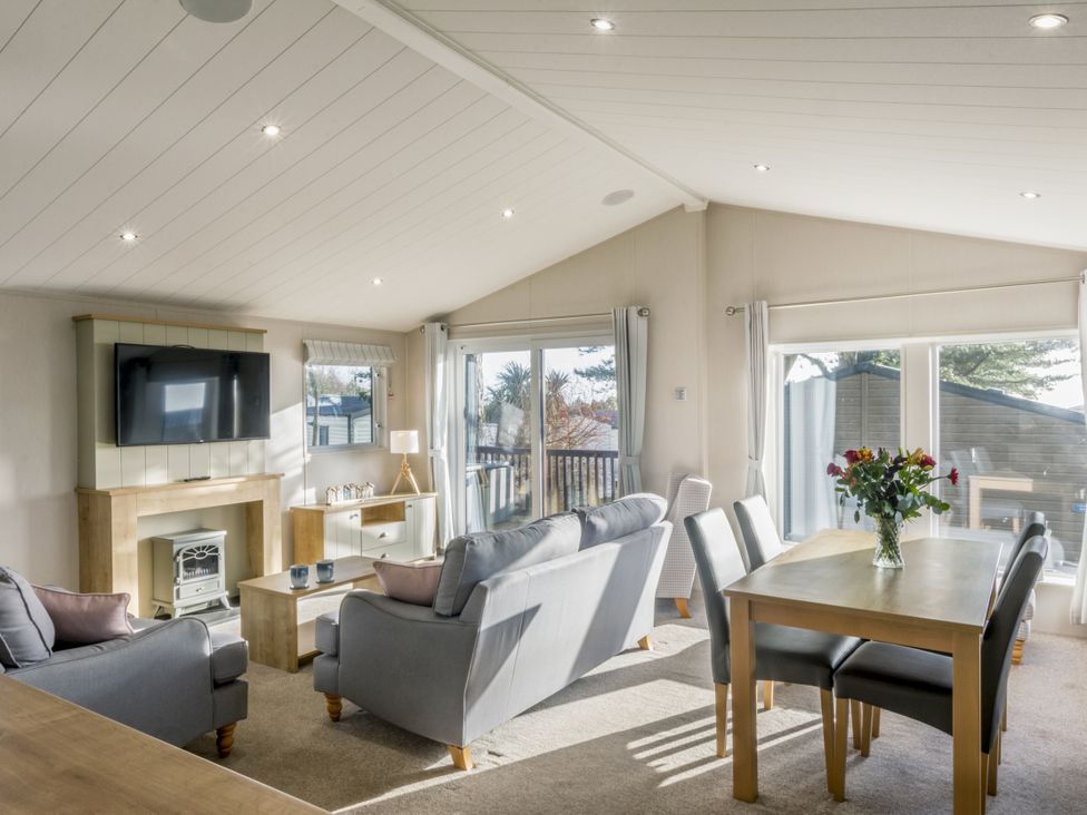 A living room with a sofa and dining table at Lodge 9 at Landscove Holiday Park Brixham