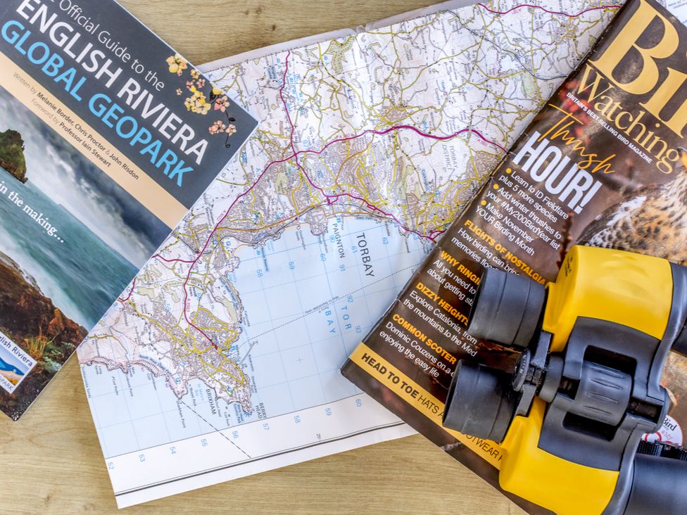 A map, a guide to the English Riviera, a bird watching magazine, and binoculars at Lodge 9 at Landscove Holiday Park, Brixham