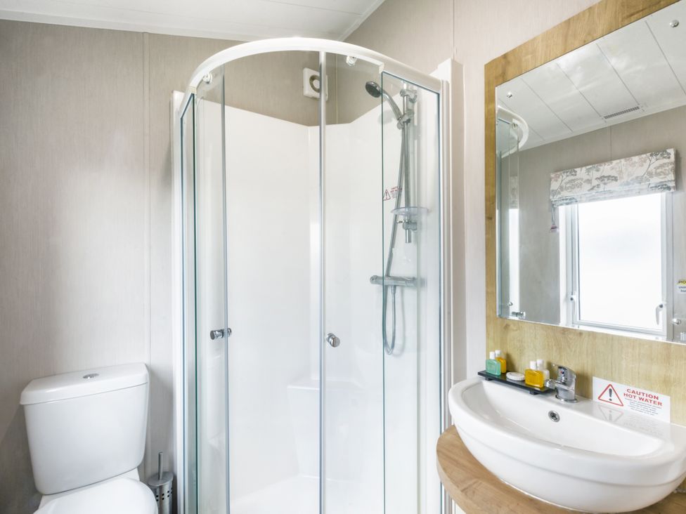 A bathroom with a shower, toilet, and sink at Lodge 9 at Landscove Holiday Park Brixham