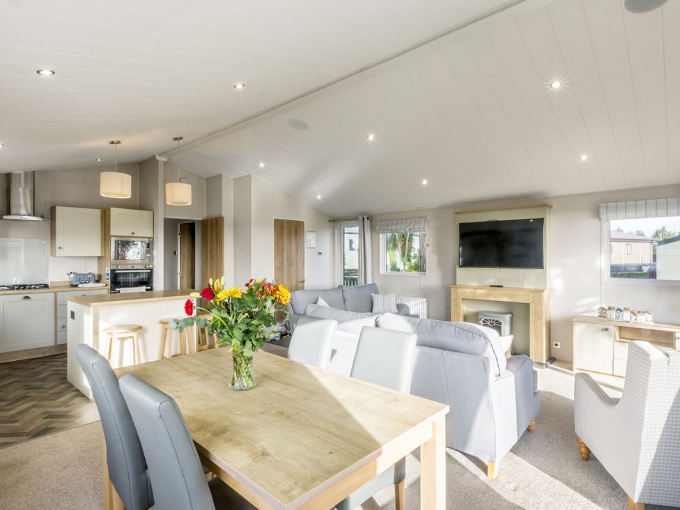 A living room with a dining table and kitchen units at Lodge 11 at Landscove Holiday Park Brixham