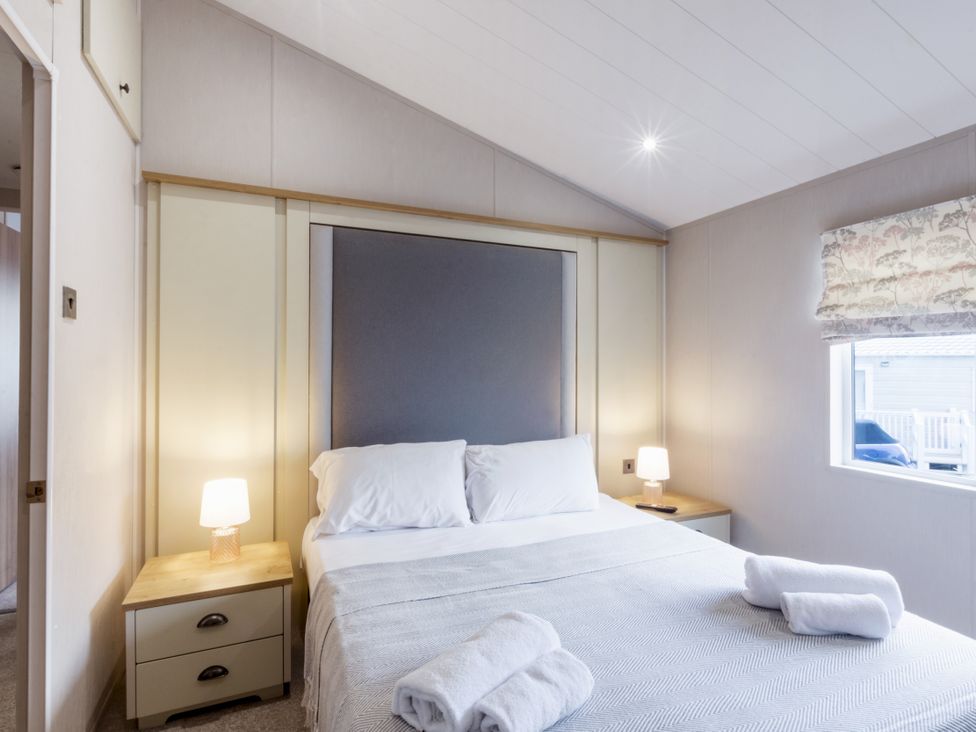 A bedroom with a bed and nightstands at Lodge 11 at Landscove Holiday Park Brixham