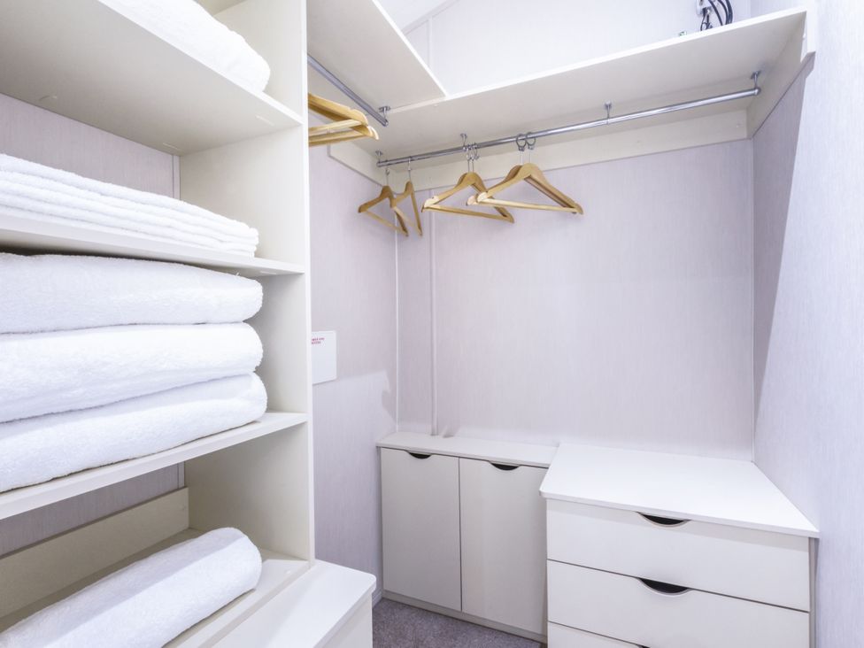 A closet with shelves, towels, and hangers at Lodge 11 at Landscove Holiday Park Brixham
