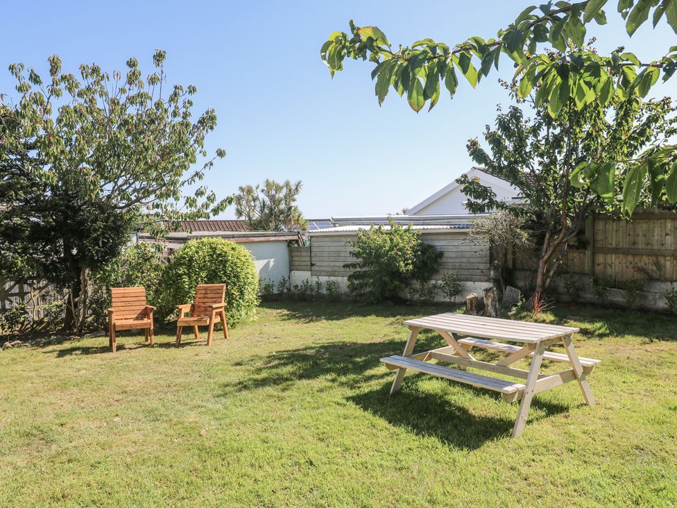 A garden with a picnic table and wooden chairs at Bod A Quinte in Carbis Bay