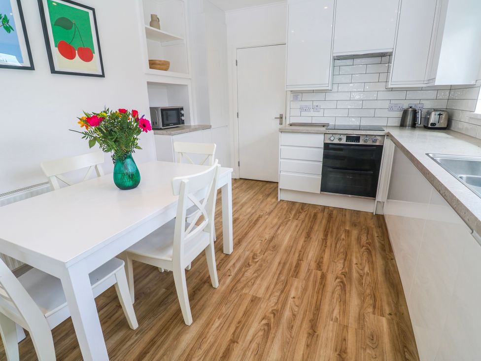 A kitchen with a table and chairs and a vase of flowers at Bod A Quinte, Carbis Bay