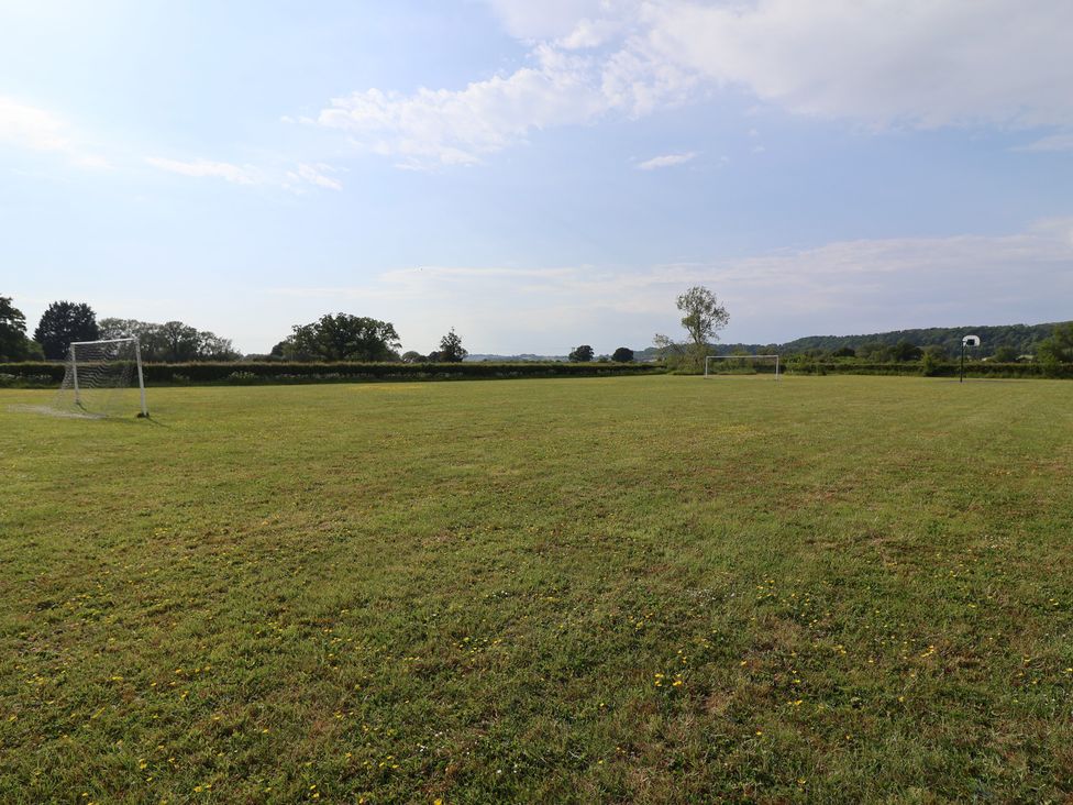An open grass field with goal posts and a basketball hoop at Metcalfe House Compton Dundon