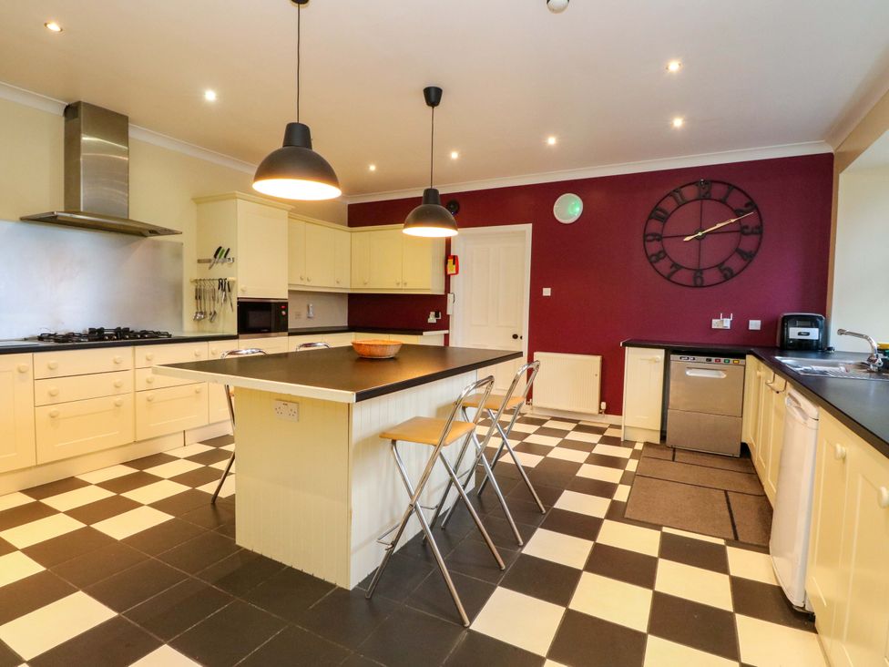 A kitchen with stove, sink, and bar stools at Rudha Na Craig Inveraray