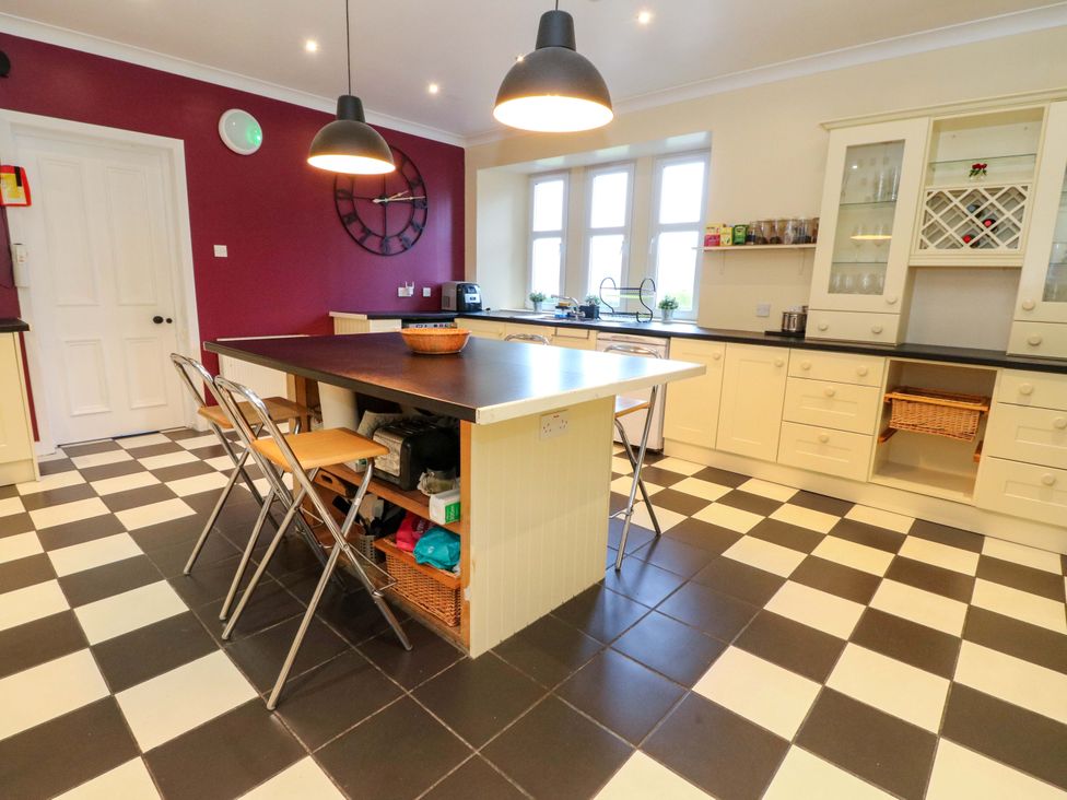 A kitchen with a central table and cabinets at Rudha Na Craig in Inveraray