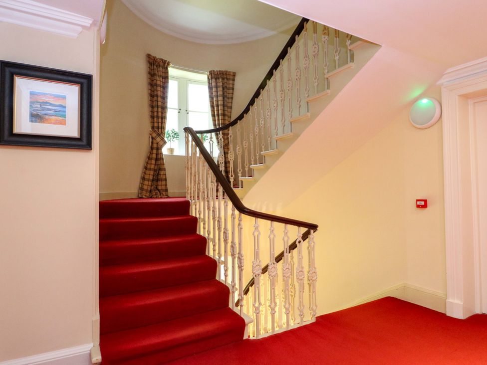 A staircase with red carpet and a window with curtains at Rudha Na Craig in Inveraray