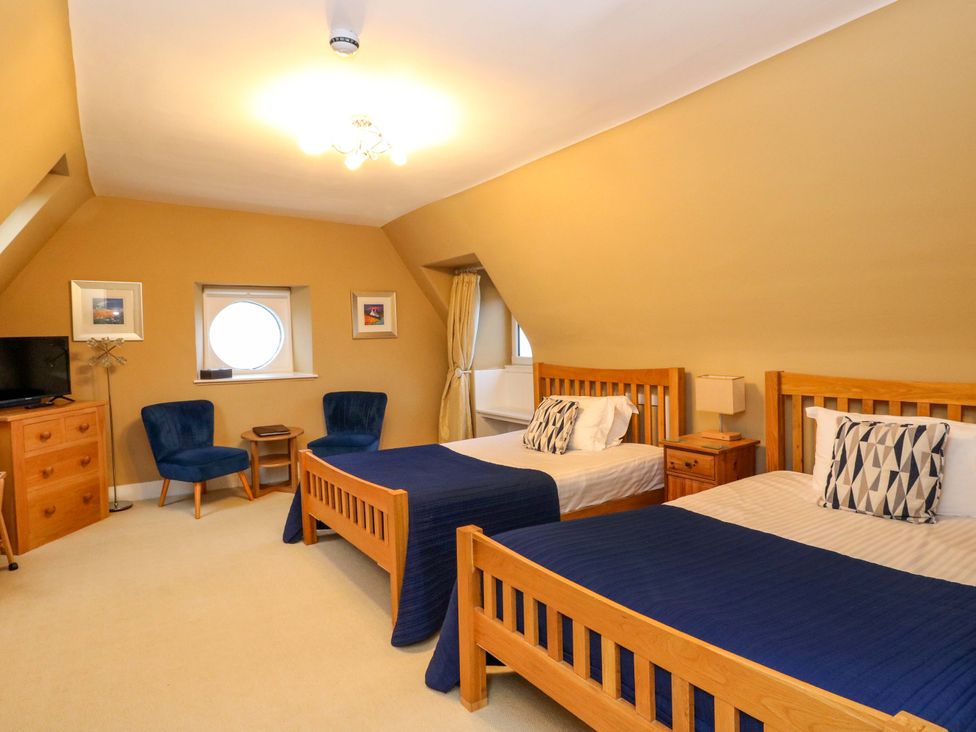 A bedroom featuring two beds with nightstands and chairs at Rudha Na Craig in Inveraray