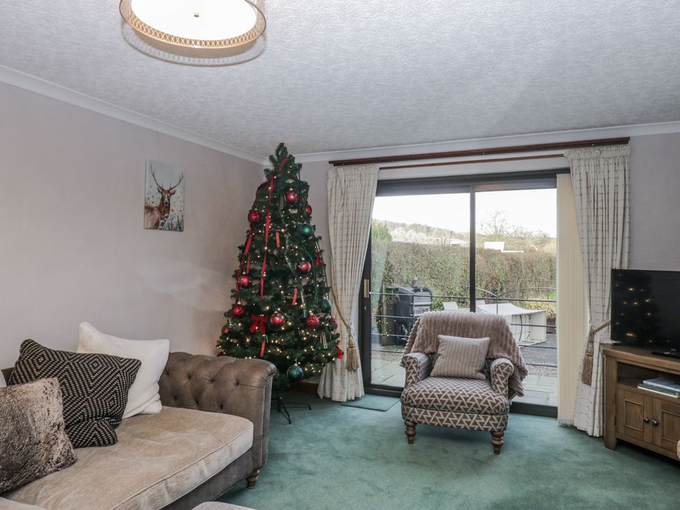 A living room with a Christmas tree and sliding door at 1 Gilpin House Levens