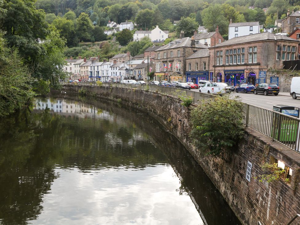 A river with buildings and cars along the road at Roseville in Cromford