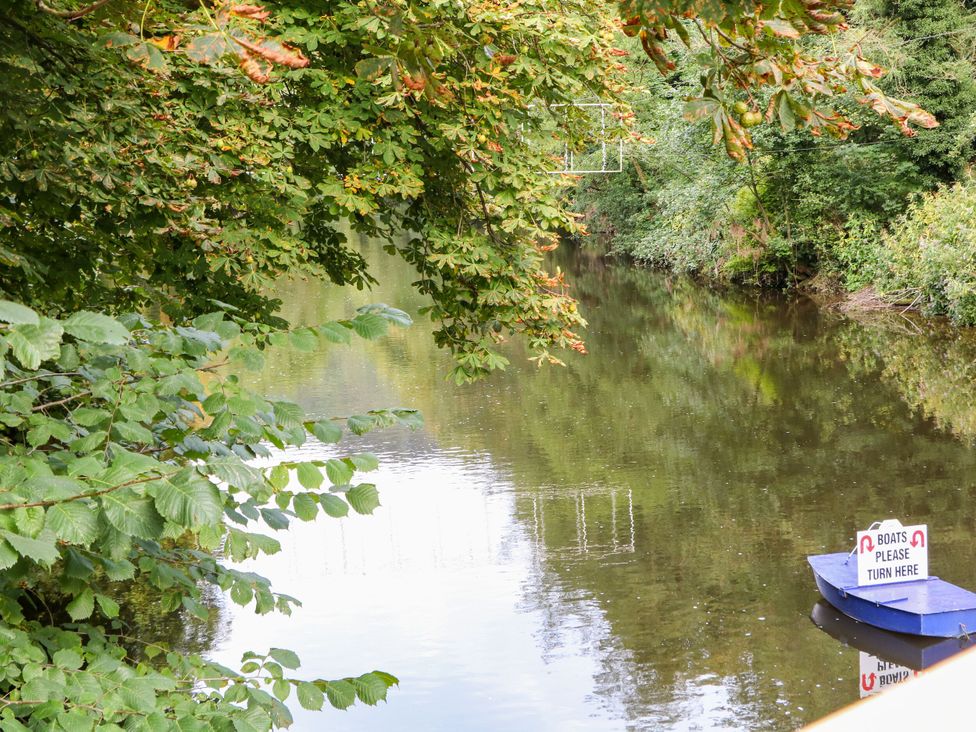 A water scene with a boat and sign near trees at Roseville, Cromford