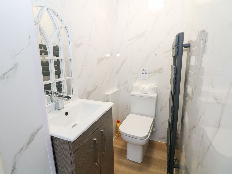 A bathroom with a sink, toilet, and mirror at Roseville in Cromford