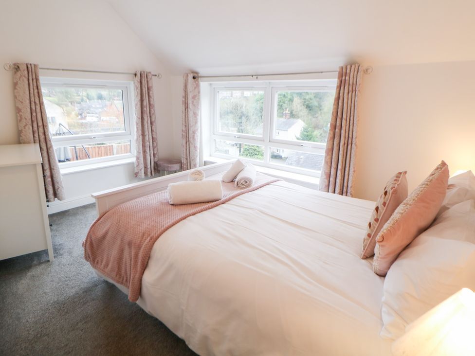 A bedroom with a bed and windows at Roseville in Cromford