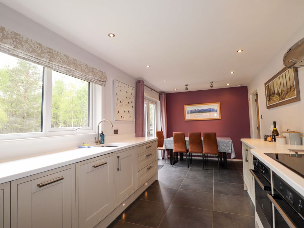 A kitchen with cabinets and a dining area at 6 Carn Dearg in Aviemore