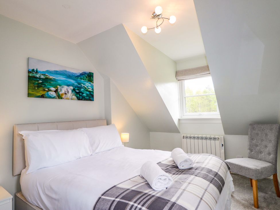 A bedroom with a bed and a chair at 6 Carn Dearg in Aviemore