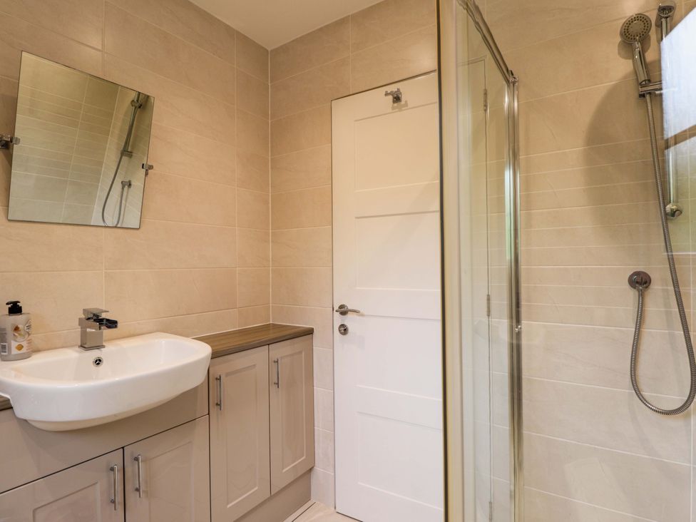 A bathroom with sink, shower, and mirror at 6 Carn Dearg in Aviemore