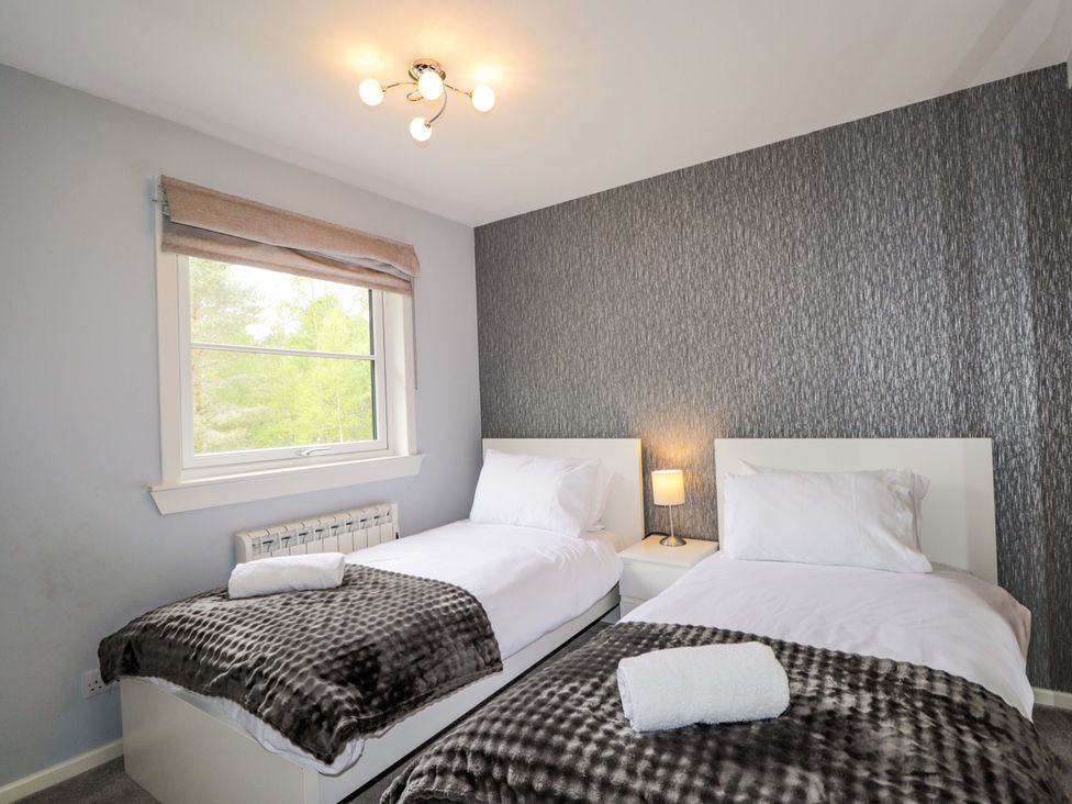 A bedroom with two beds and a bedside table at 6 Carn Dearg in Aviemore