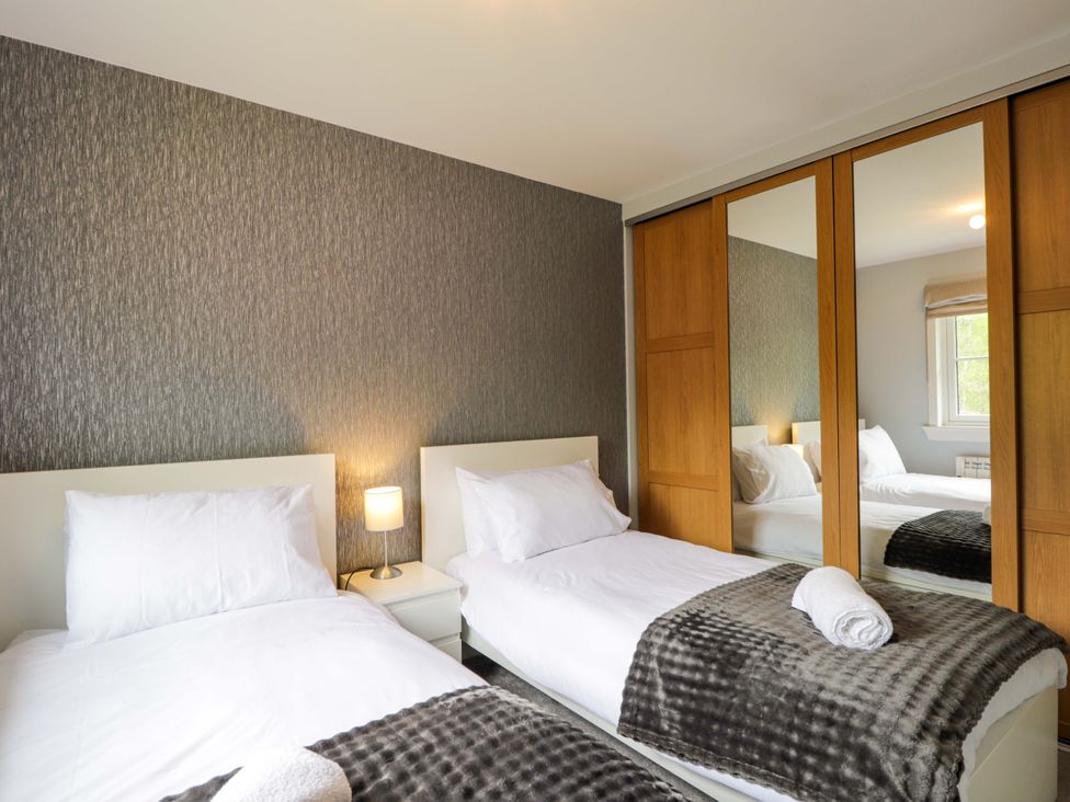 A bedroom with two beds and a bedside table at 6 Carn Dearg in Aviemore