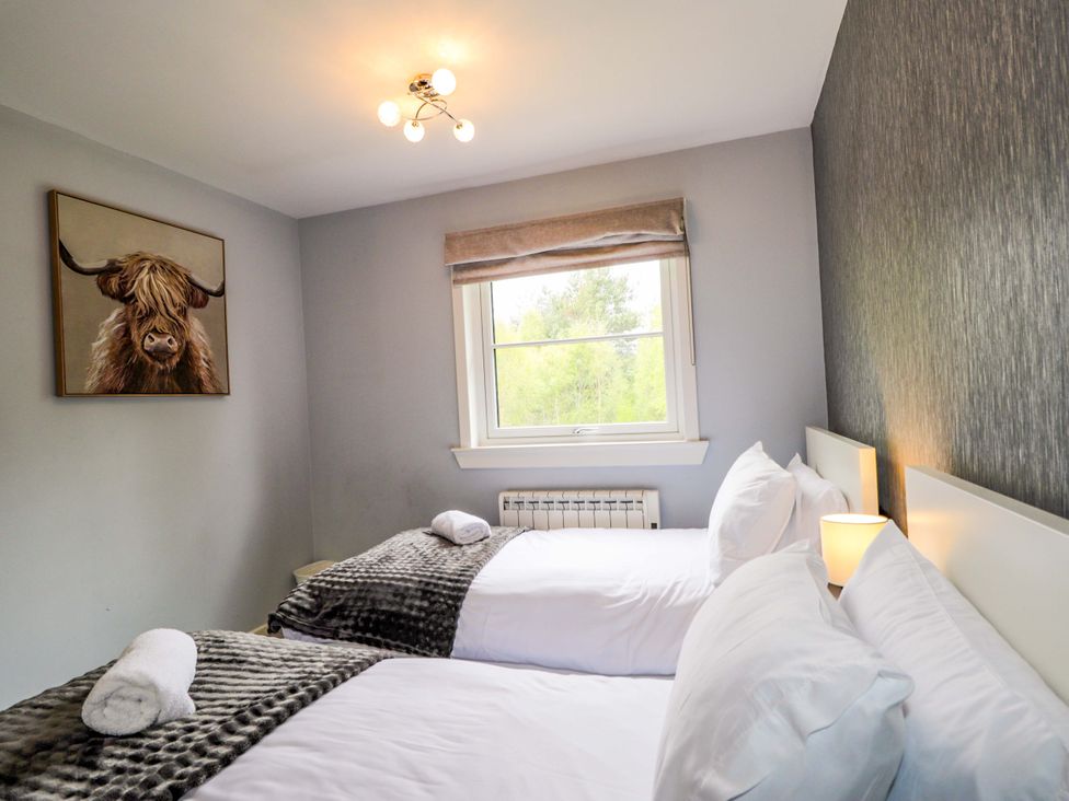 A bedroom with two beds and a painting at 6 Carn Dearg in Aviemore