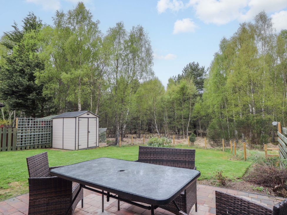 A garden with a table and chairs and a shed at 6 Carn Dearg in Aviemore