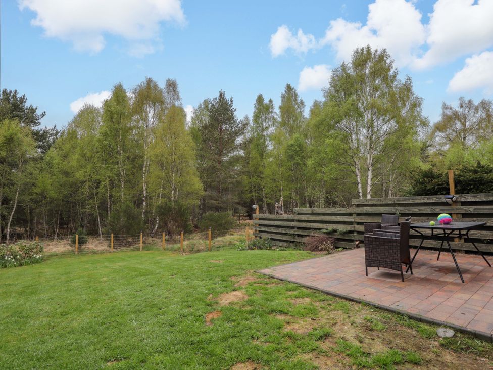 A garden with a patio, table, and chairs at 6 Carn Dearg in Aviemore