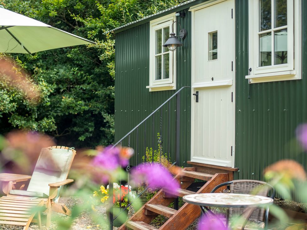 A green shed with steps and seating area at Collen in Aberaeron
