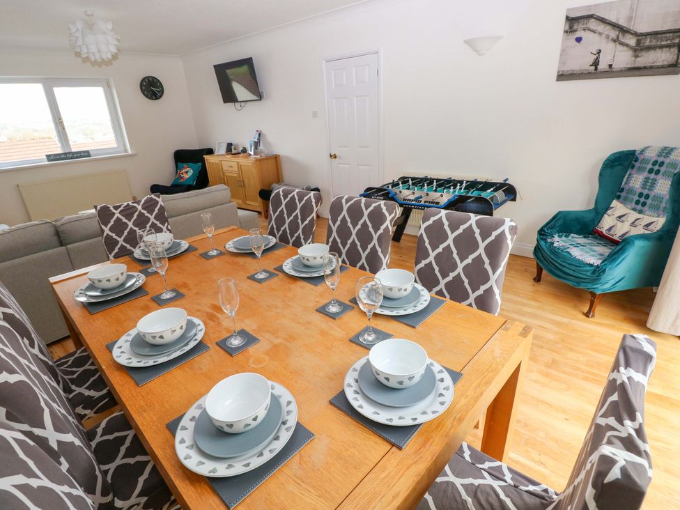 A dining room with a table set for meals at 15 Lawnswood in Saundersfoot
