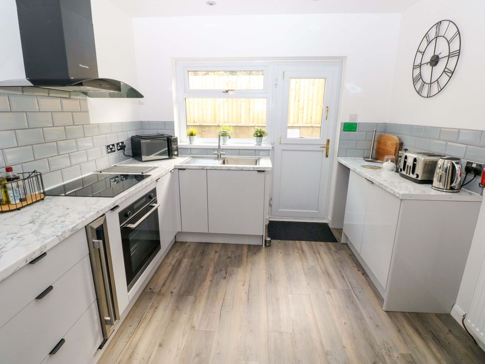 A kitchen featuring cabinets, a sink, stove, and appliances at 15 Lawnswood in Saundersfoot